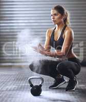 Ready to start lifting. Shot of a young woman coating her hands with sports chalk before a kettle bell workout.