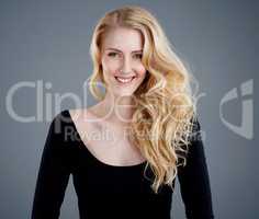 Hair as luminous as the sun. Studio portrait of an attractive young woman with beautiful long blonde hair posing against a gray background.