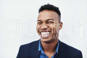 Im the happiest man in the whole world. Studio shot of a young businessman smiling and in good spirits against a grey background.