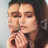 The mirror does not define your beauty. Shot of a beautiful young woman leaning against a mirror.