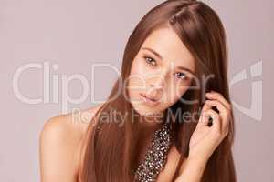 Youthful beauty. Beautiful young woman wearing a beaded necklace against a pink background.