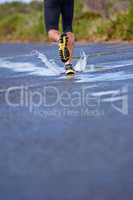 Hit the road - whatever the weather. Cropped image of a runners legs as he runs onwards.