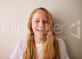 Laugh at yourself, life is short. Shot of a young woman smiling and standing against a wall at home.