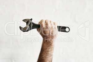 The all powerful monkey wrench. Shot of an unrecognizable handyman holding up a monkey wrench.