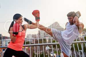Thats a great block. Shot of a young couple going through some kickboxing routines outdoors on a bridge.