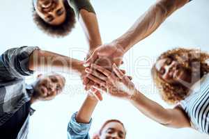 The team that dreams continuously achieves. Low angle shot of a group of businesspeople joining their hands together in a huddle.