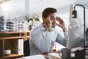 Im trying so hard not to lose my mind. Shot of a young businessman looking stressed out while working late on a computer in an office.