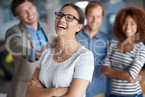 Lifes great with the support of my colleagues. Young businesswoman laughing happily with supportive colleagues behind her.