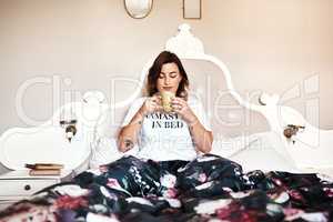 I cant face the day without having coffee first. Shot of a beautiful young woman having coffee in bed.