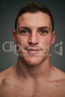 You cant spoil his mood. Studio closeup of a cheerful young man standing against a grey background while looking into the background.