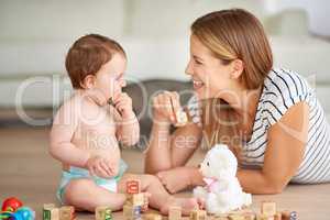 Making early childhood experiences fun and entertaining. Shot of an adorable baby girl and her mother playing with wooden blocks at home.