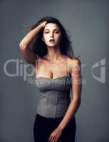 Shes got that supermodel type of vibe. Studio portrait of an attractive young woman posing against a grey background.