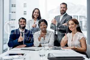 Team spirit promotes greater accomplishment. Portrait of a group of businesspeople showing thumbs up together in an office.