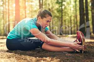 I stretch to prevent injuries. Shot of a sporty young woman doing stretch exercise while out in nature.