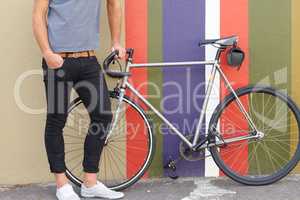 Do you like my ride. Cropped shot of a stylishly dressed young man standing next to a bicycle against a colourful background.