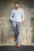 Casual urban style is his signature look. Shot of a handsome young man posing against an urban wall.