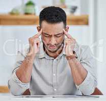 My head feels like its about to explode. Shot of a young businessman experiencing a headache while at work.