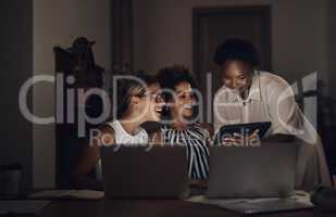 Some of the biggest successes are built in the dark. Shot of a group of young businesswomen using a laptop and digital tablet during a late night at work.