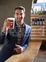 Cheers to you. Shot of a handsome young man enjoying an ale at the bar.