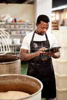 I log the times for every task. Cropped shot of a man using a digital tablet while working in a bakery.