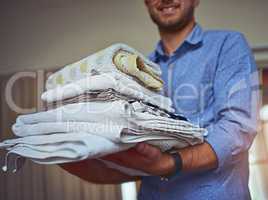 Anyone call for clean towels. Cropped shot of a young man holding a load of freshly folded clean laundry.