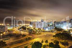 Nighttime in a bustling city. Scene of an inner city intersection with lights and clouds overhead.