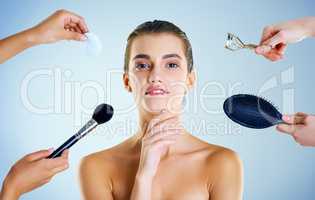 Tools to get my look just right. Studio portrait of a beautiful young woman with an assortment of beauty tools around her against a blue background.