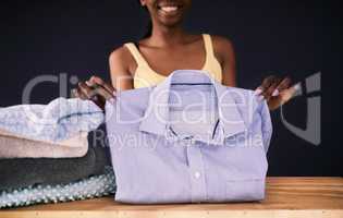 Its laundry day. Shot of a young woman folding laundry against a dark background.