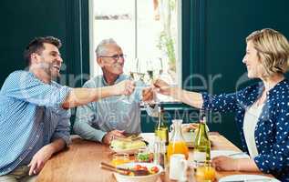 The meal was extraordinary. Shot of a cheerful family sharing a celebratory toast together while being seated around the dinner table at home.