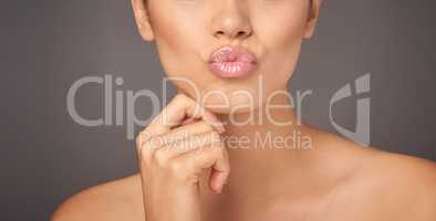 Pucker and pout. Closeup studio shot of a woman with gorgeous glossy lips against a gray background.