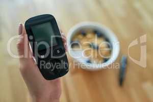 Monitoring her blood glucose levels after every meal. Closeup shot of an unrecognizable woman testing her blood sugar level with a glucose meter.