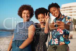 Strike a pose ladies. Shot of three attractive young women laying down on the beach and taking selfies together during the day.