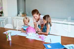 Moms always make the best teachers. Shot of a young mother helping her two small children with their art project at home.