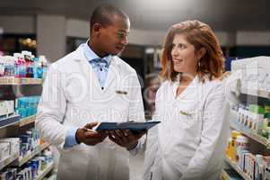 Making notes on whats needed around their dispensary. Shot of two pharmacists working together in a chemist.