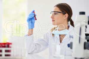 Gaining deeper insights to help develop a cure. Cropped shot of a young female scientist examining a test tube in a lab.