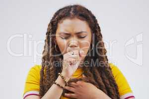 Shes coming down with something. Studio shot of an attractive young woman coughing against a grey background.