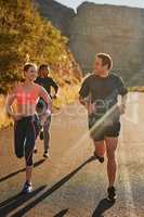 They encourage each other to go faster and farther. Shot of a fitness group running along a rural highway.