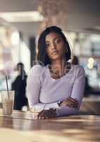 Theres always time for a coffeeshop stop. Shot of a beautiful young woman drinking a iced coffee in a cafe.