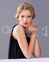 Every woman needs a touch of glamour. A gorgeous young woman in an evening gown while isolated on a grey background.