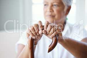 Time to get up and go. Closeup shot of a senior woman holding her cane while sitting in the old age home.