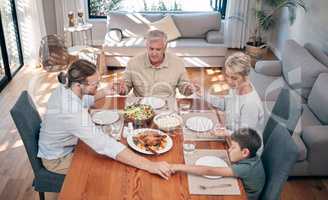 Bless the food before us and the family beside us. Shot of a family holding hands in prayer before having a meal together at home.