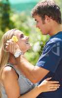 Shes my precious flower. A young man placing a flower over his girlfriends ear while looking lovingly at her.