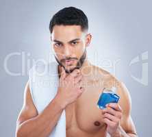 The cologne that keeps you guessing. Studio shot of a handsome young man applying cologne against a grey background.