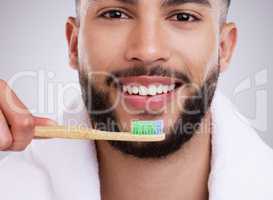 Remember to use circular motions. Shot of a handsome young man brushing his teeth against a studio background.