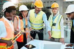 We have a lot to get through. Shot of a diverse group of contractors standing outside together and having a discussion over building plans.