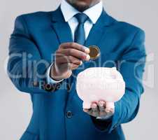 Todays savings are tomorrows money in the bank. Studio shot of a businessman holding a piggybank and putting a bitcoin in it against a grey background.