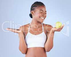 I eat for energy and nourishment. Studio shot of a young woman holding up a slab of chocolate and an apple in the other hand.