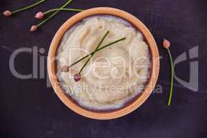 I totally regret eating healthy today, said no one ever. Overhead shot of cauliflower mash puree in a wooden bowl on a black table.