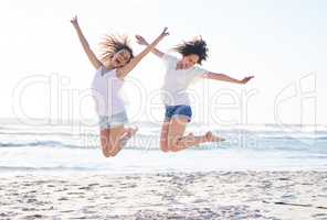 Celebrate your friendship everyday. Shot of two young women jumping for joy at the beach.