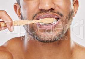Starting my morning off fresh. Shot of an unrecognizable man brushing his teeth against a grey background.